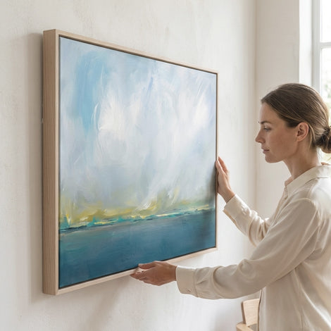 Woman hanging Divinity canvas print in white oak frame by Julia Contacessi