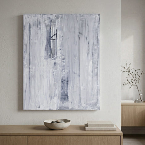 Undone abstract painting by artist Julia Contacessi hangs on a wall above a wooden cabinet with decorative items.