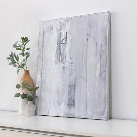 Abstract art piece on a white wall with decorative vases and plants.
